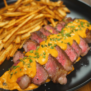 Medium-rare steak frites topped with creamy Asian-inspired sauce and served with crispy seasoned fries
