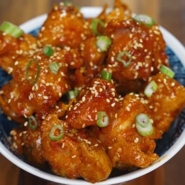 Soy garlic Korean fried chicken topped with sesame seeds and green onions in a bowl