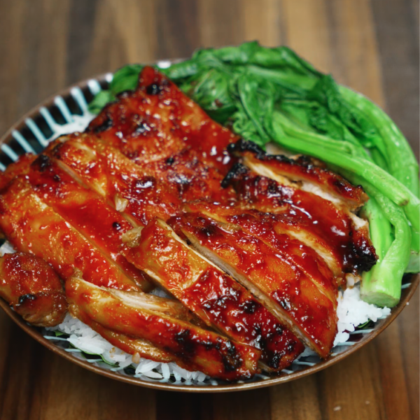 A full view of a BBQ gochujang chicken rice bowl featuring thick slices of caramelized chicken glazed in a spicy, sweet, and smoky Korean-style sauce. Nestled over fluffy white rice and accompanied by blanched bok choy, this dish balances heat and freshness in a visually vibrant and satisfying dinner perfect for Asian recipe lovers.