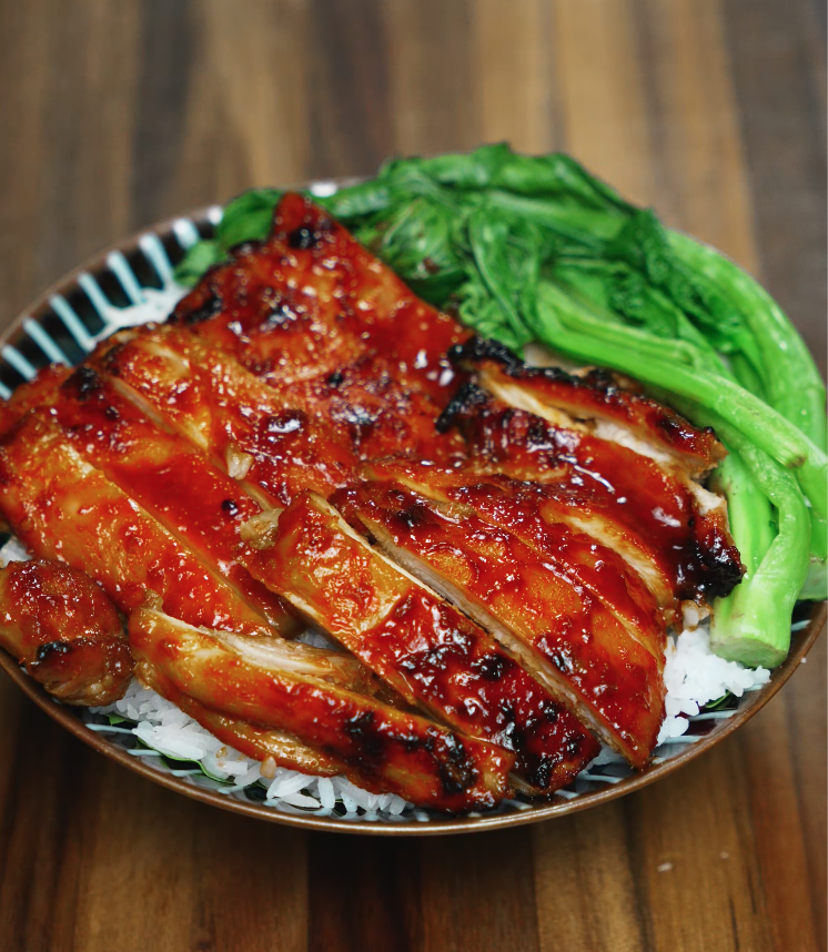 A full view of a BBQ gochujang chicken rice bowl featuring thick slices of caramelized chicken glazed in a spicy, sweet, and smoky Korean-style sauce. Nestled over fluffy white rice and accompanied by blanched bok choy, this dish balances heat and freshness in a visually vibrant and satisfying dinner perfect for Asian recipe lovers.