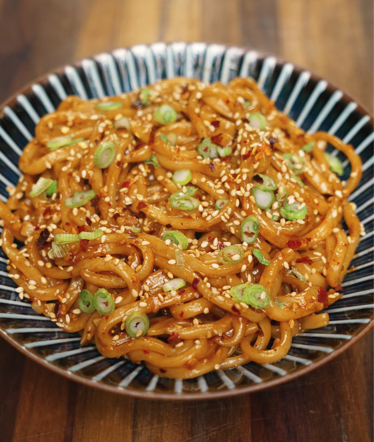 Bowl of chili garlic butter noodles garnished with sesame seeds, red pepper flakes, and sliced scallions — quick and easy spicy noodle recipe.