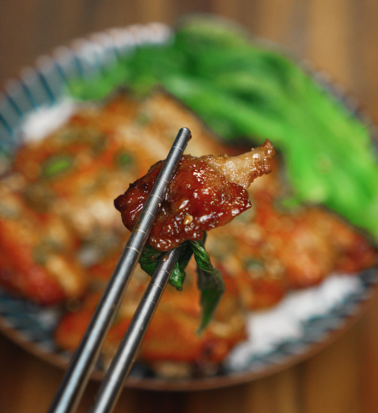 Bite of glazed chicken bulgogi held with chopsticks — sweet and savory Korean chicken perfect over rice.