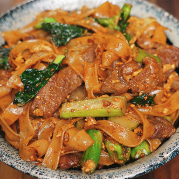 A bowl of freshly cooked Pad See Ew filled with seared beef, Chinese broccoli, scrambled egg, and wide rice noodles coated in sweet soy sauce. A satisfying and savory Thai street food classic.