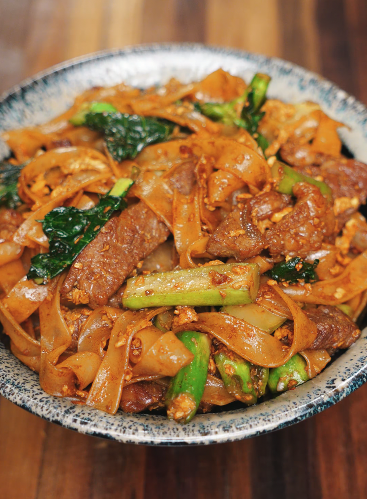 A bowl of freshly cooked Pad See Ew filled with seared beef, Chinese broccoli, scrambled egg, and wide rice noodles coated in sweet soy sauce. A satisfying and savory Thai street food classic.