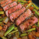 A close-up of a fork holding a perfectly cooked slice of steak above a bed of glazed vegetables. The steak’s interior is tender and rosy while the outer layer is seared for maximum flavor.