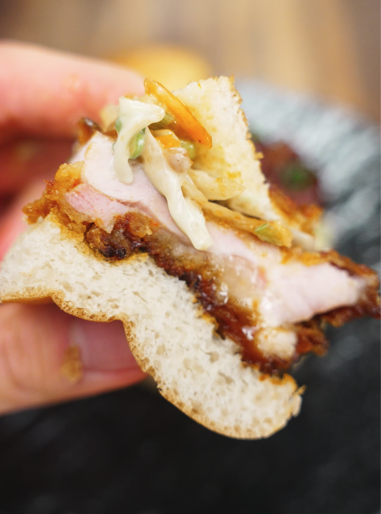 A juicy bite of the fried chicken sandwich shows off the layers—crispy crust, tender meat, crunchy coleslaw, and soft bread all in one cross-section.