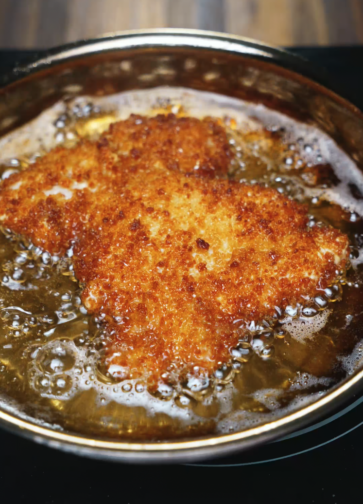 Breaded chicken katsu frying in oil until perfectly golden brown and crispy – key component of chicken katsu curry recipe.