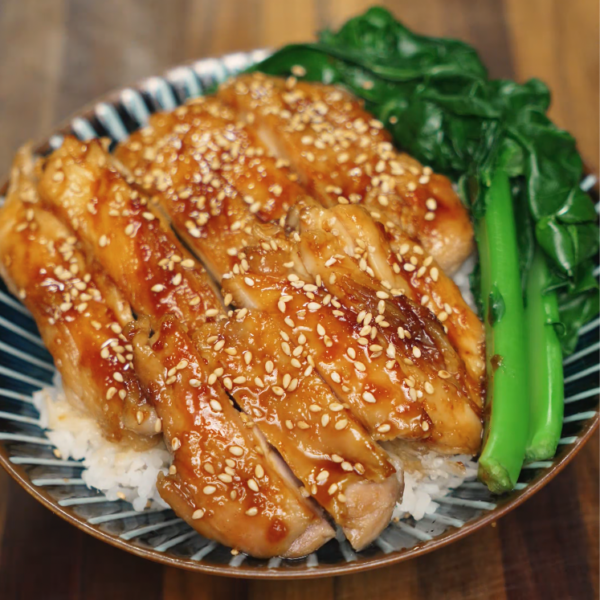 A bowl of sliced honey garlic chicken served over steamed jasmine rice with sautéed Chinese broccoli (gai lan). The chicken is coated in a glossy honey garlic glaze and topped with sesame seeds for texture and added flavor. This protein-packed Asian rice bowl is perfect for lunch, dinner, or quick meal prep recipes.