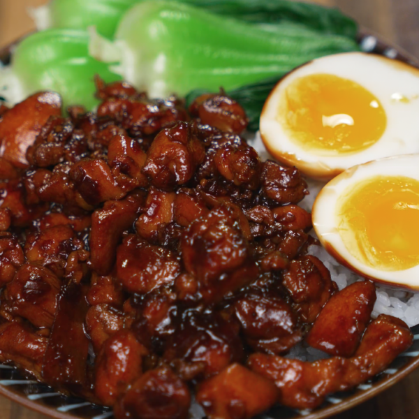 Bowl of Coca Cola braised chicken served over rice with bok choy and jammy eggs — sweet, sticky, and rich chicken dinner.