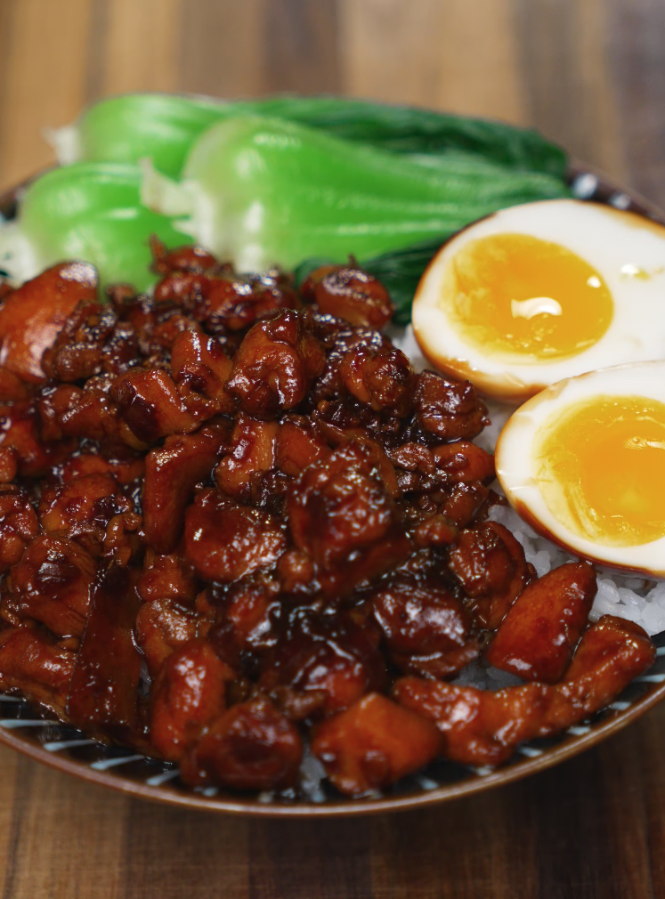 Bowl of Coca Cola braised chicken served over rice with bok choy and jammy eggs — sweet, sticky, and rich chicken dinner.