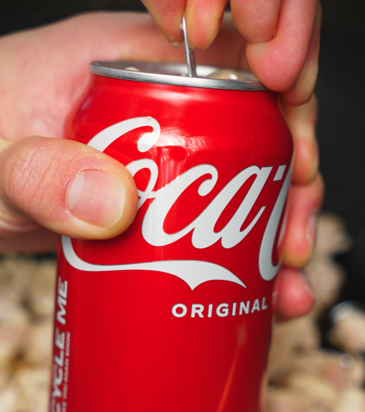 Hand opening a can of Coca Cola — used as a sweetener and glaze base for Coca Cola braised chicken.