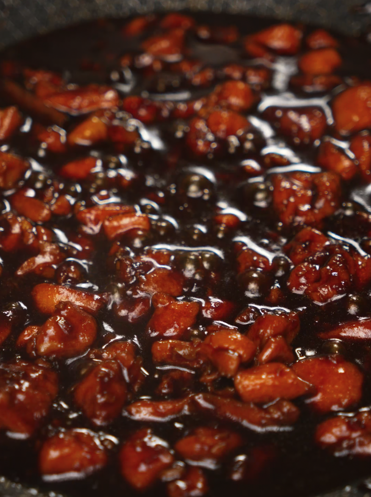 Coca Cola braised chicken bubbling in sauce — sticky, sweet glaze forming as the chicken cooks down.