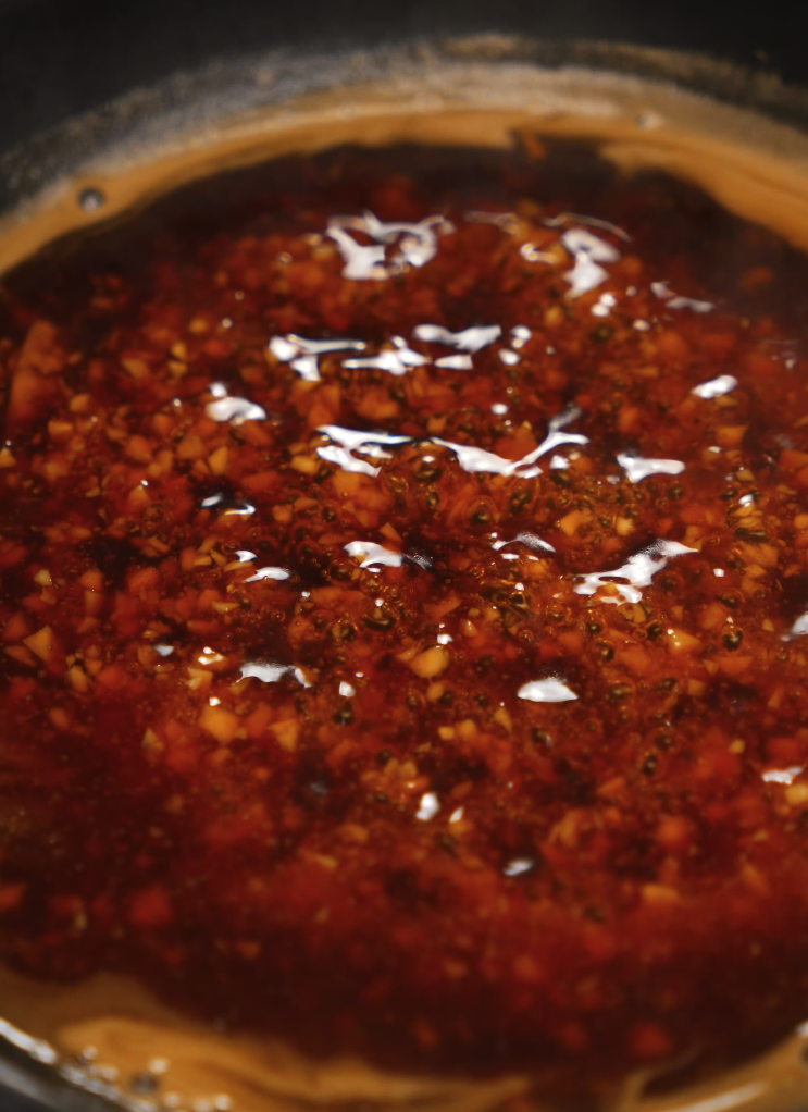 A bubbling pan of rich, homemade soy garlic sauce made with minced garlic, soy sauce, sugar, and a hint of chili oil, creating a glossy, caramelized glaze perfect for Korean fried chicken.