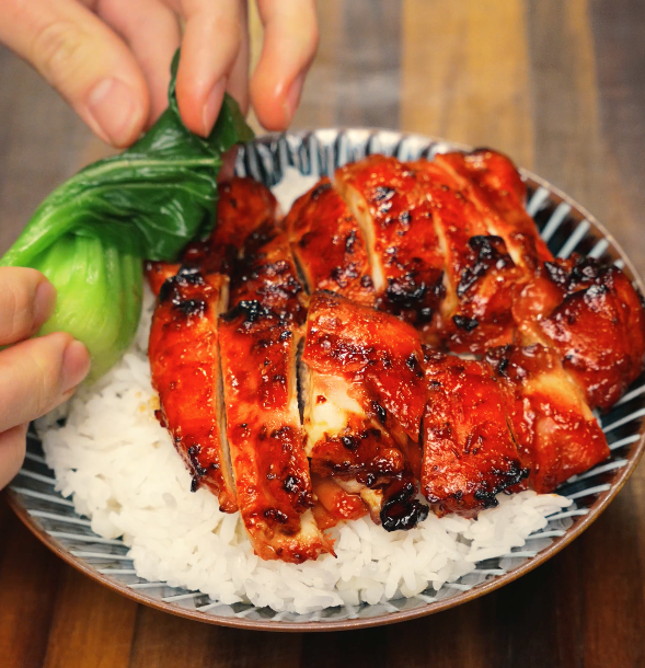 Placing bok choy next to Char siu chicken over a fresh bowl of warm white rice