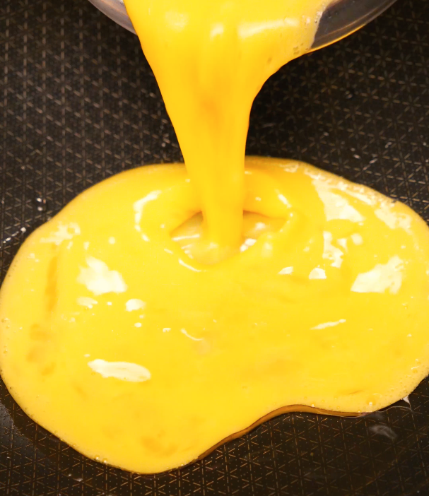 pouring whisked eggs into pan for egg fried rice – beginner-friendly cooking step