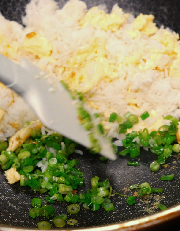 stir-frying chopped green onions into egg fried rice – savory and aromatic rice recipe