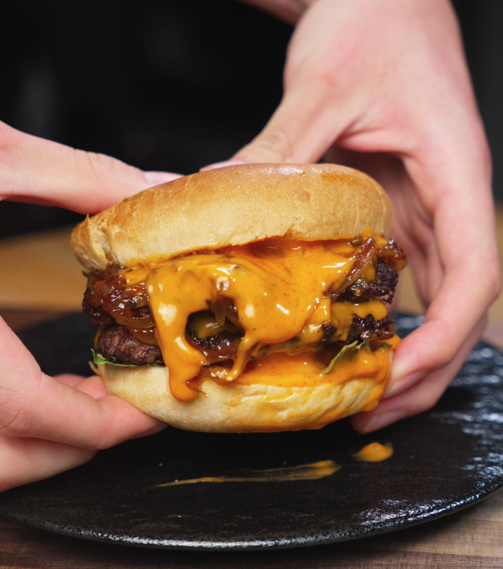Stacking caramelized onions, cheesy patties, and spicy mayo inside toasted burger buns, bringing together all the rich layers of the Asian Smash Burger.