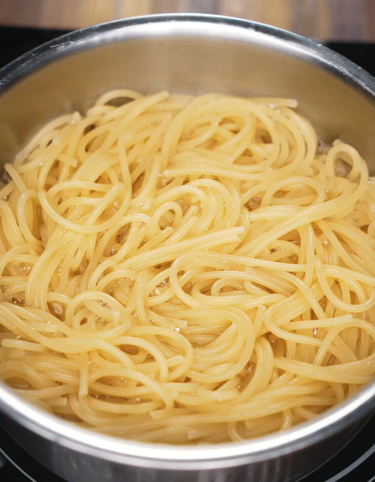 Spaghetti boiling in a stainless steel pot, cooked until al dente for the chili oil pasta.