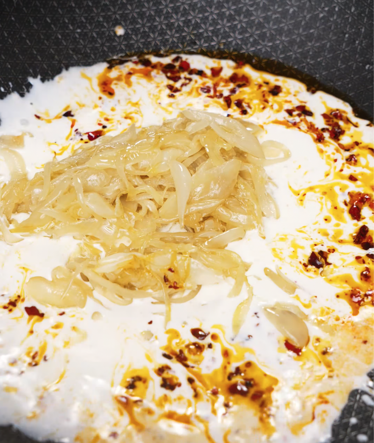 Caramelized onions added to a creamy chili oil sauce in a pan to build the flavor base.