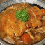 Final bowl of Chicken Katsu Curry Udon featuring crispy panko-fried chicken over rich Japanese curry and udon noodles, garnished with scallions.