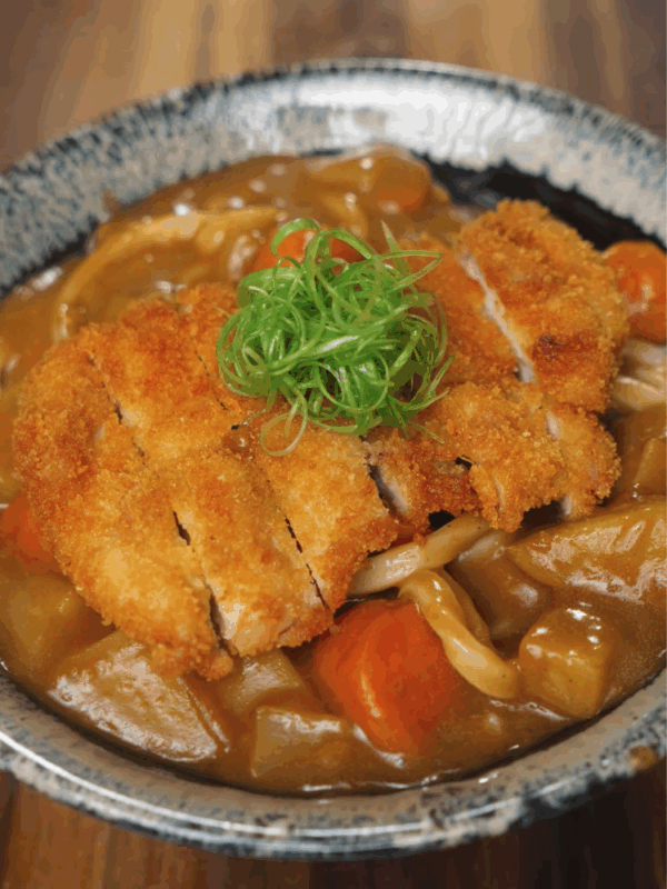 Final bowl of Chicken Katsu Curry Udon featuring crispy panko-fried chicken over rich Japanese curry and udon noodles, garnished with scallions.