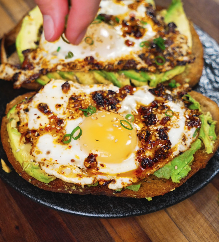 Sprinkling scallions and sesame seeds over the finished chili oil egg toast for a final touch.