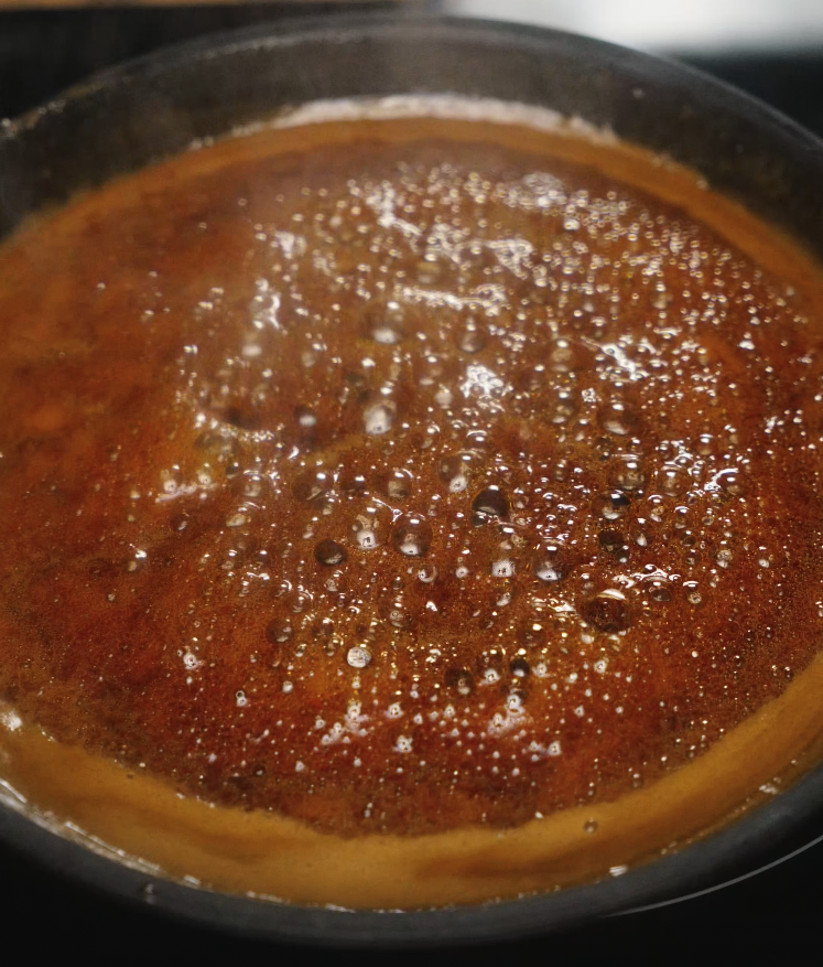 A rich, amber-colored honey garlic sauce bubbling gently in a pan on the stove.