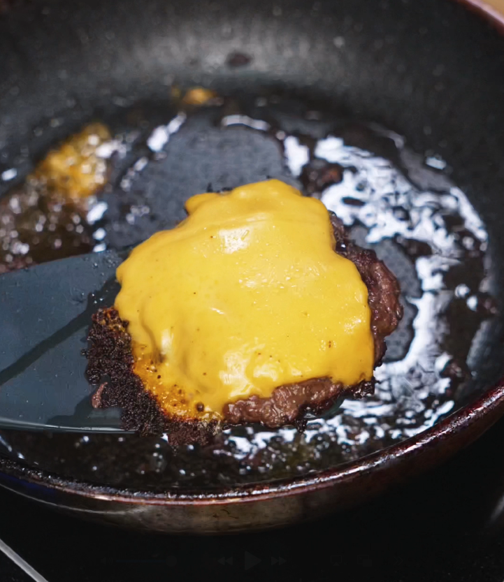 Cheddar cheese melted over flipped smash patties in a pan, locking in flavor and creating the gooey layer for the Asian Smash Burger.