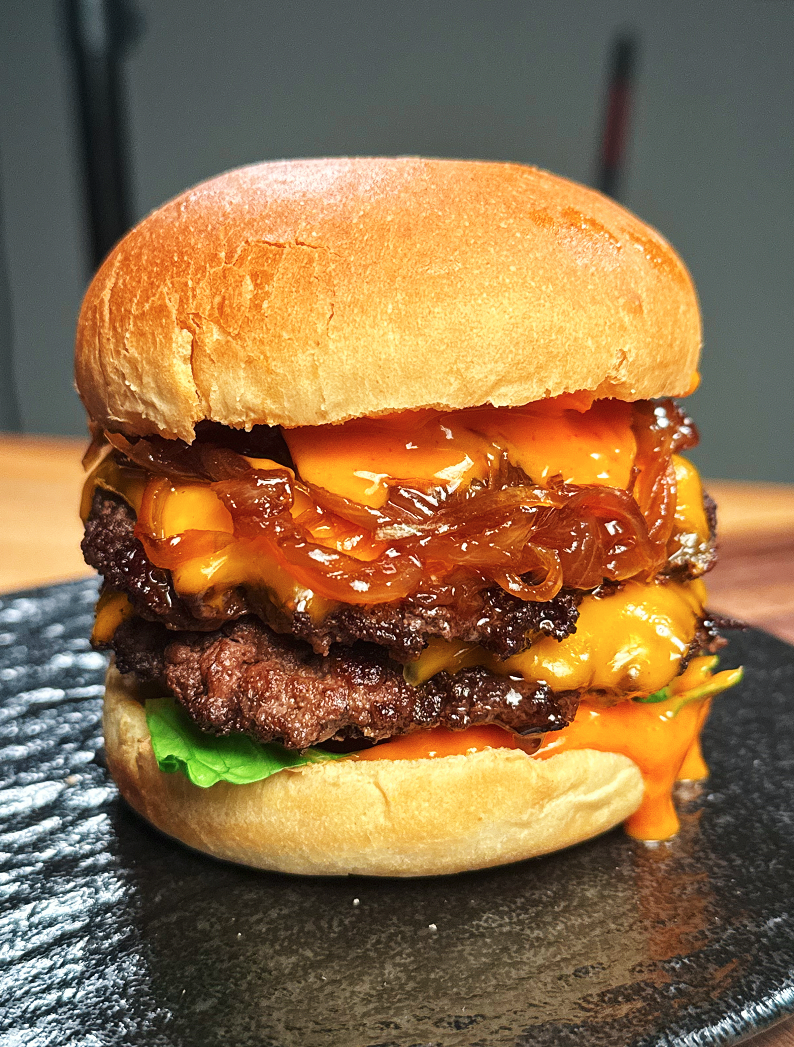 Stacking caramelized onions, cheesy patties, and spicy mayo inside toasted burger buns, bringing together all the rich layers of the Asian Smash Burger.