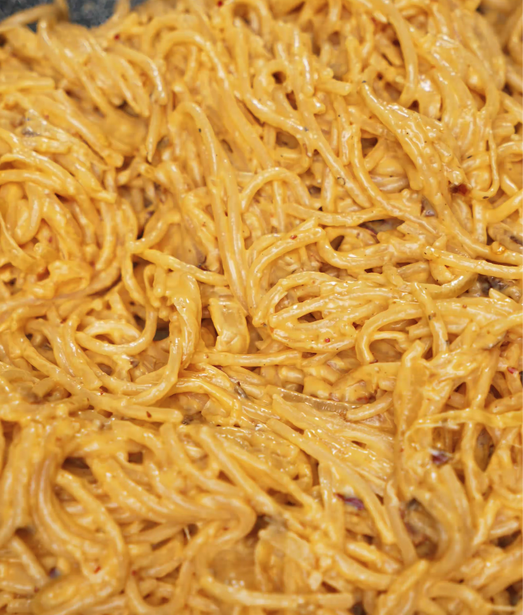 Spaghetti fully mixed into the rich, creamy chili oil sauce, coating each noodle evenly.