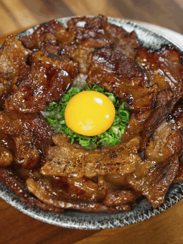 A complete sticky pork rice bowl featuring glossy pork, fluffy rice, and fresh garnishes, ready to enjoy.