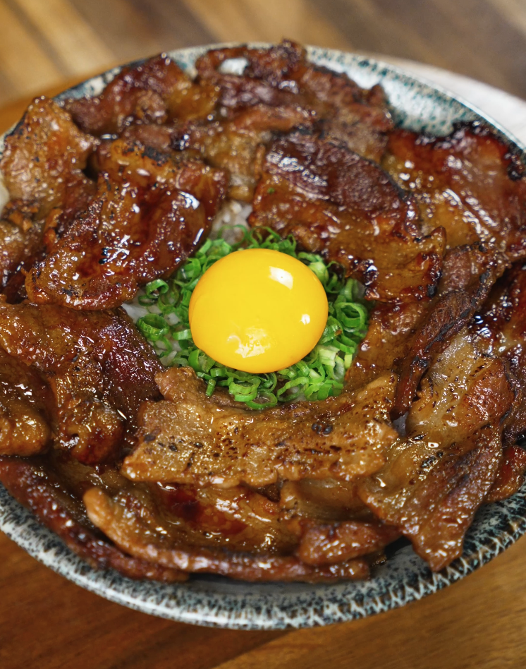 A complete sticky pork rice bowl featuring glossy pork, fluffy rice, and fresh garnishes, ready to enjoy.