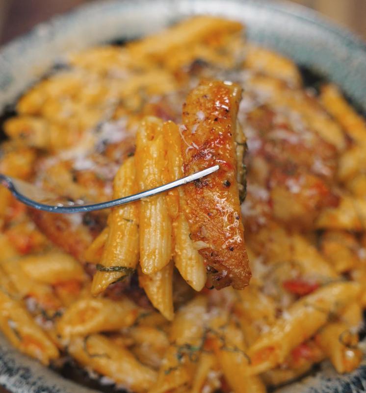 A fork lifts a bite of penne pasta and juicy chicken coated in creamy sauce, highlighting the irresistible texture of Marry Me Chicken pasta.