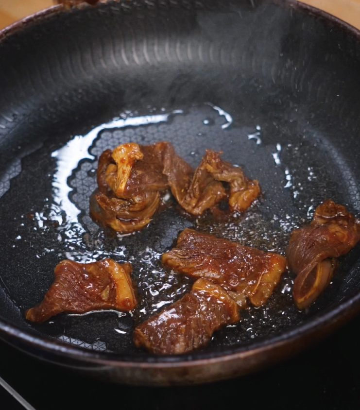 Searing marinated beef slices in a hot, oiled pan to develop a rich, brown crust and lock in flavor for tapa.