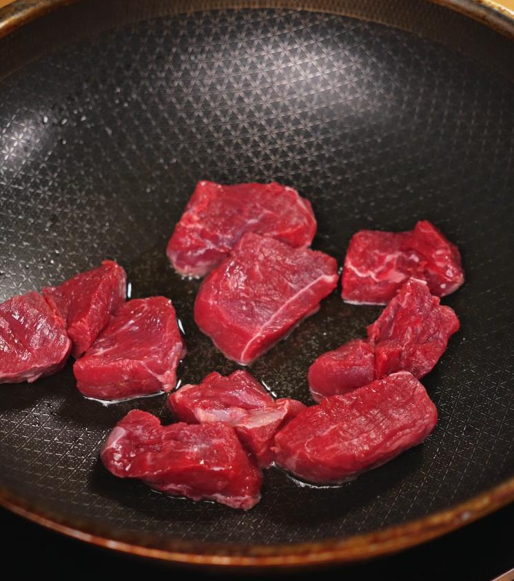 Raw beef cubes are seared in a large skillet to develop a rich brown crust, an essential step for building flavor in Japanese curry.