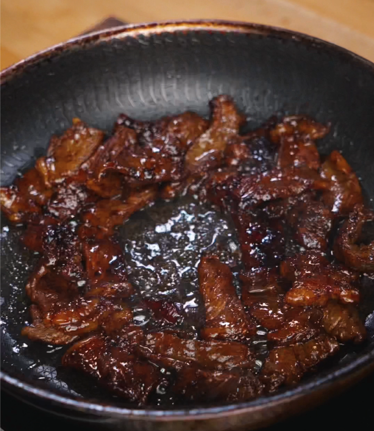 Searing marinated beef slices in a hot, oiled pan to develop a rich, brown crust and lock in flavor for tapa.