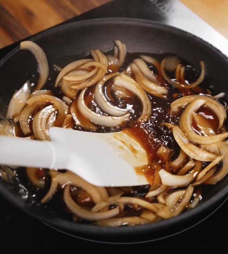 Sliced onions cooking in a sweet soy-based broth, the savory base for the katsudon egg mixture.