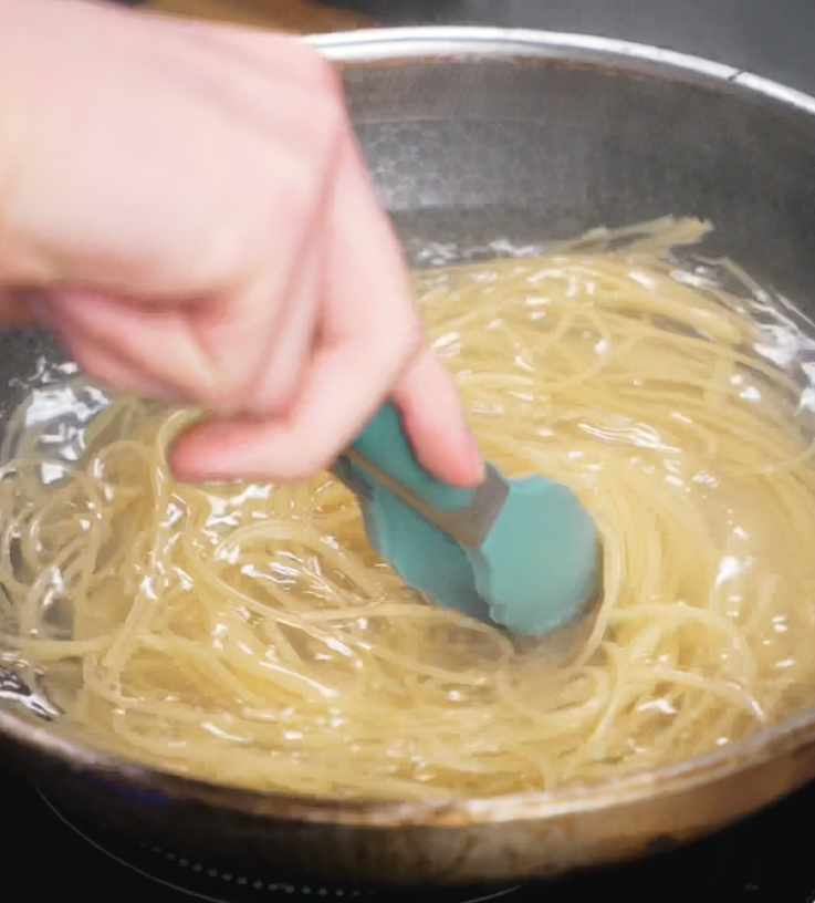 Spaghetti is stirred in a pot of boiling salted water until just shy of al dente, ready to be tossed in the sauce.