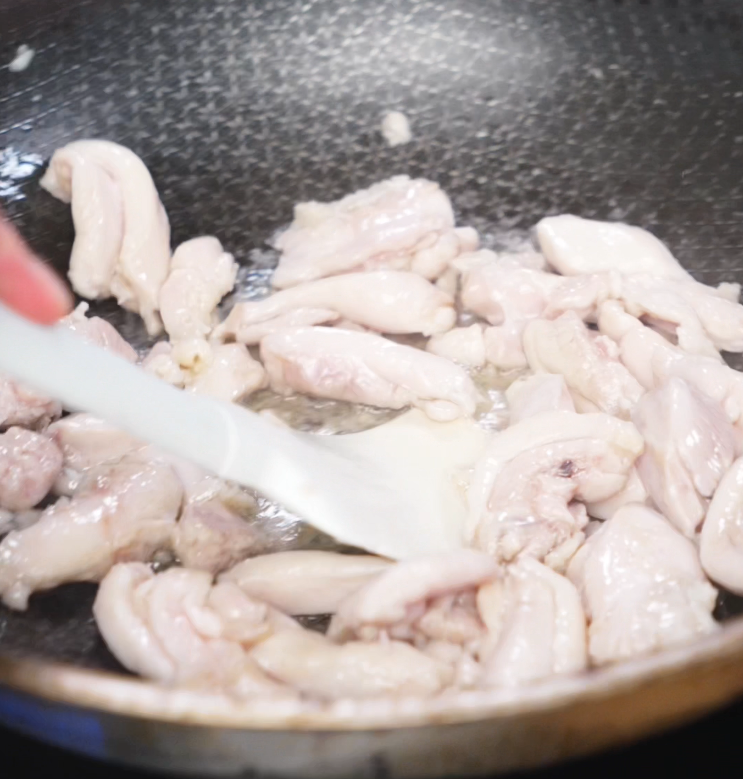 Marinated chicken thighs cook in a hot pan until lightly browned and tender, forming the protein base of the dish.