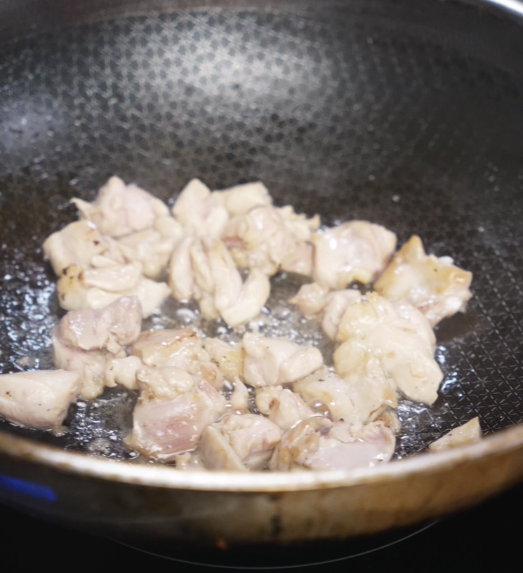 Cubes of chicken thigh cook in a hot pan until browned and golden, forming the protein base of the garlic butter chicken bowl.