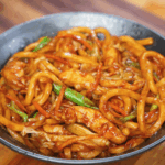 A full bowl of chicken yaki udon filled with glossy noodles, carrots, cabbage, and scallions coated in a rich soy-based stir-fry sauce.
