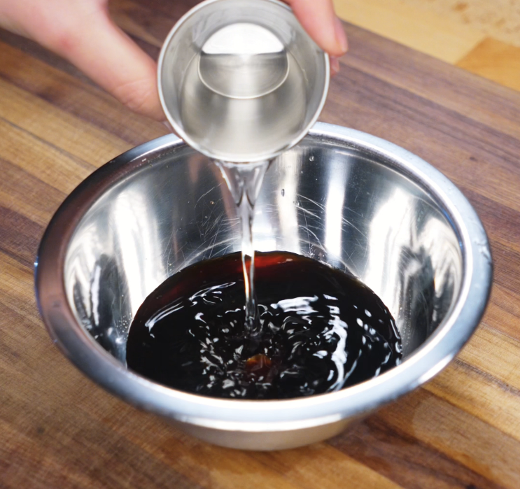 Sake is poured into a bowl of soy sauce and mirin, forming the savory-sweet marinade that gives ginger pork its signature flavor.