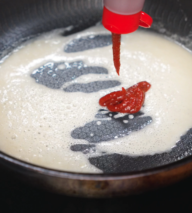 A spoonful of gochujang paste is added to the roux, infusing the sauce with deep red color and a spicy, umami kick.