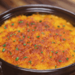The baked gochujang mac and cheese emerges golden brown and bubbling, with flecks of parsley adding a pop of green.