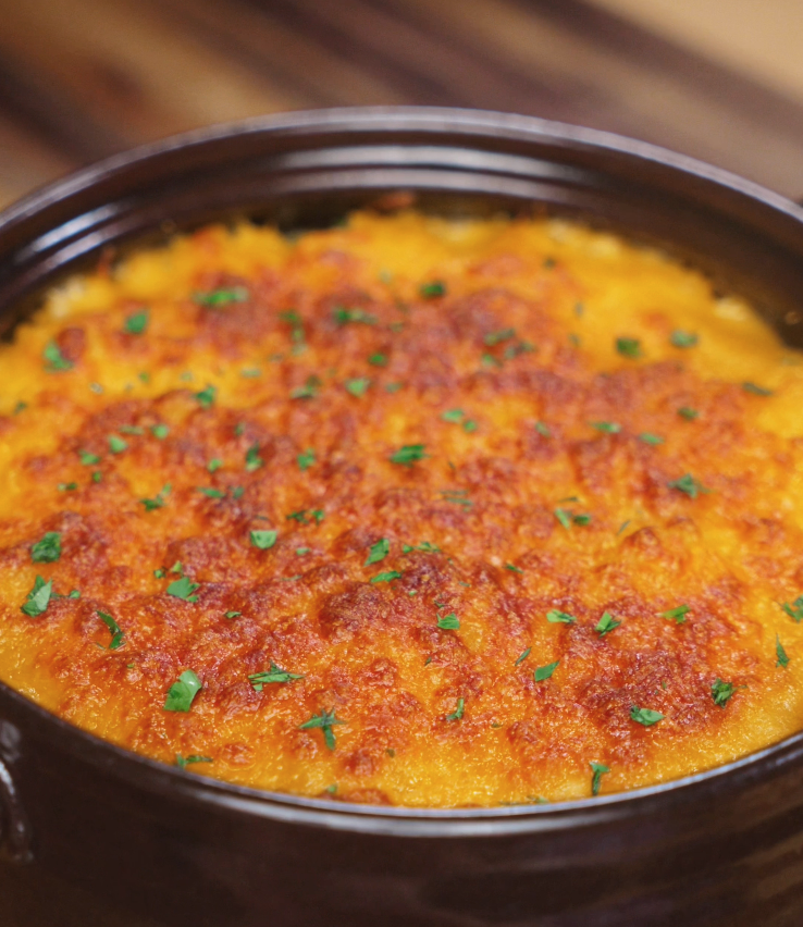 The baked gochujang mac and cheese emerges golden brown and bubbling, with flecks of parsley adding a pop of green.