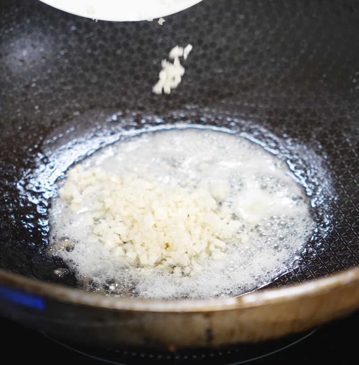 Minced garlic sizzles in melted butter inside a nonstick pan, releasing its aroma for the garlic butter sauce.
