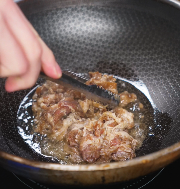 Thinly sliced, marinated beef sizzles in a hot pan, developing a deep brown crust as it cooks for the fried rice base.