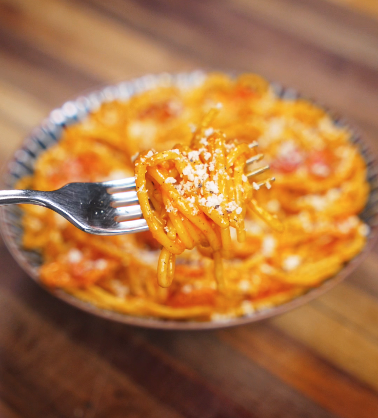 A fork lifts a perfect twirl of gochujang carbonara, showcasing the creamy, glossy sauce clinging to the noodles.