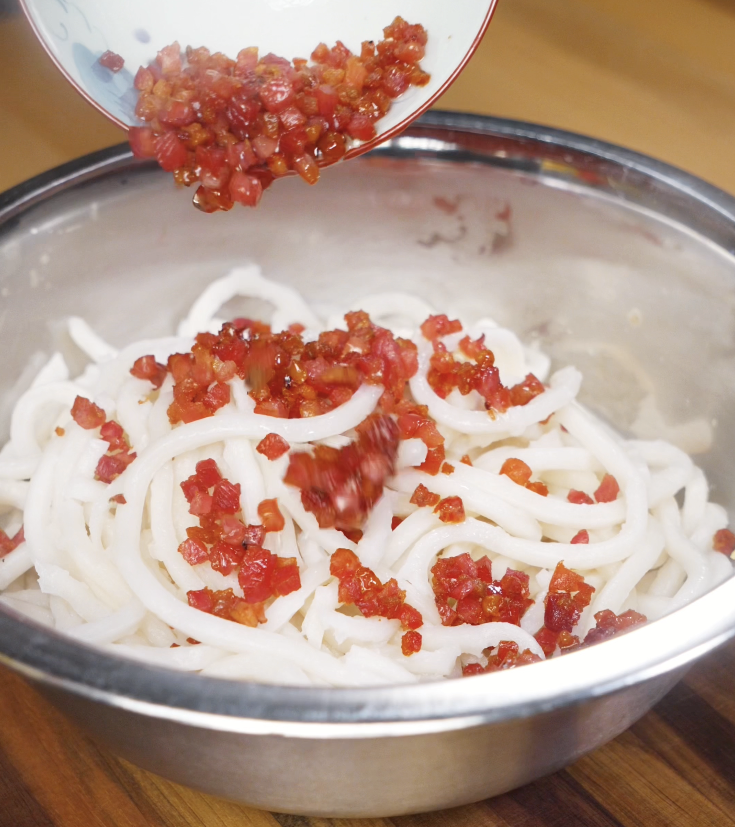 Crispy pancetta pieces are added to the bowl of udon noodles for a savory, smoky flavor boost.