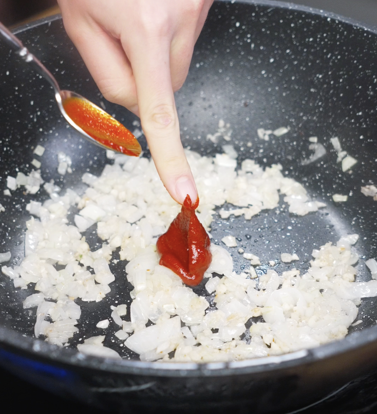 A spoonful of red gochujang paste is added to the sautéed onions and garlic to build the base of the creamy sauce.